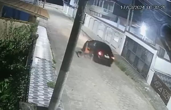 Imagem de segurança mostra homem pendurado na porta de um carro preto