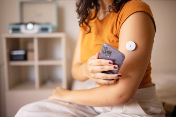 Mulher com diabetes mede a glicose no braço com smartphone - Metrópoles