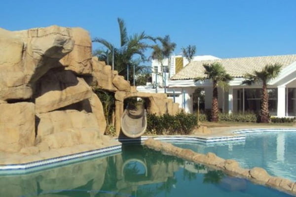 Foto colorida de piscina com toboágua e casa ao fundo que pertence ao ex-jogador Robinho - Metrópoles