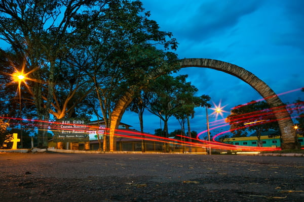 Foto colorida da entrada da Cidade Alto Paraíso, GO com carros passando durante a Blue Hour