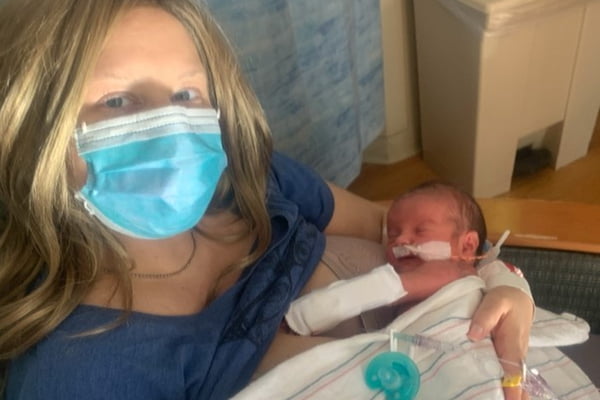 Foto mostra mulher loira de máscara e bebê recém-nascido - Metrópoles