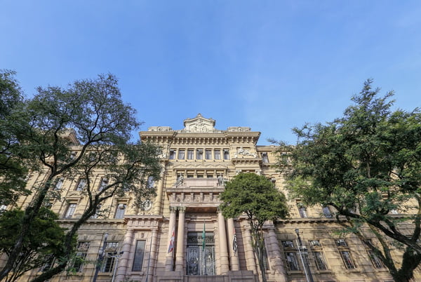 Imagem colorida mostra fachada do TJSP, prédio de estilo clássico, em dia de céu claro