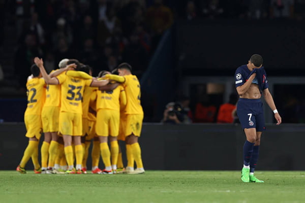 Imagem colorida de time do Barcelona comemorando gol enquanto Mbappé lamenta derrota - Metrópoles