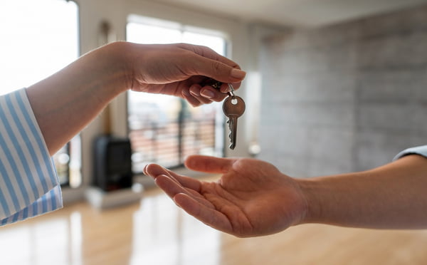 Foto colorida de agente imobiliário dando as chaves de sua nova casa para um homem - Metrópoles