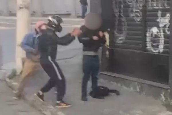 Foto colorida de homem abordado por bandido, que usa capacete de moto - Metrópoles