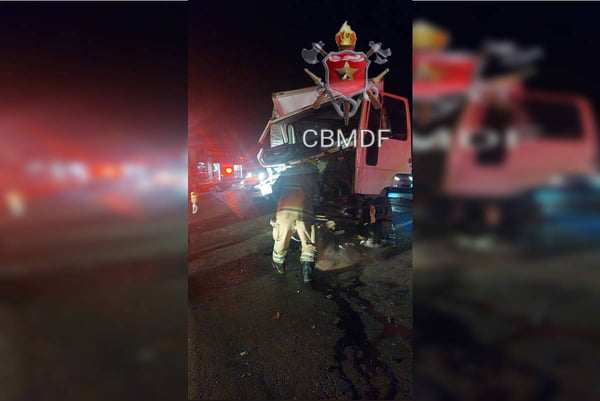 Foto colorida tirada à noite de homens de uniforme em frente aos escombros de um caminhão