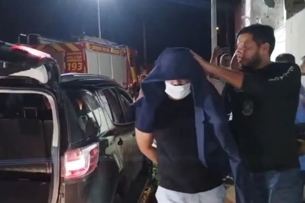 Imagem colorida de suspeito sendo conduzido por policiais