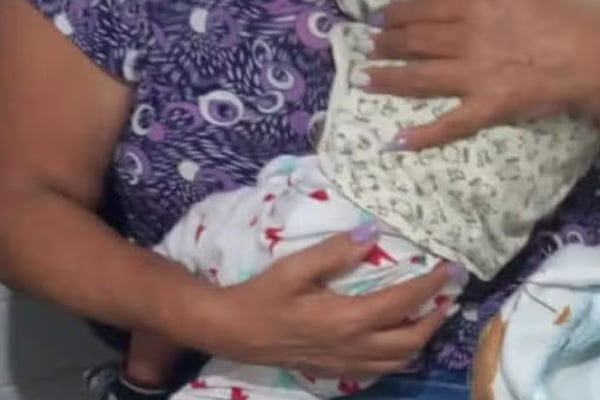 Imagem colorida de bebê em colo de uma mulher - Metrópoles