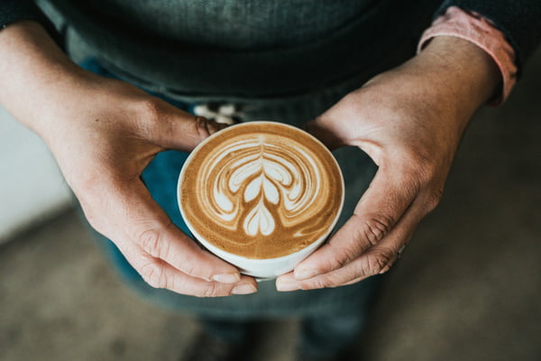 Fotografia colorida mostrando duas mãos segurando caneca com café-Metrópoles