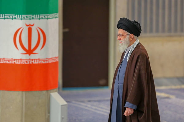 Imagem colorida mostra líder supremo do Irã, Ali Khamenei, caminhando em direção a bandeiro do país - Metrópoles