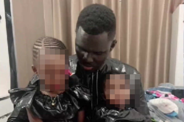 Homem negro com duas crianças no colo
