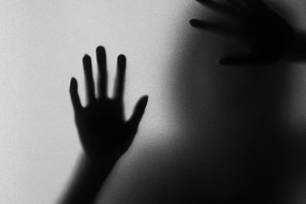 Imagem em preto e branco para ilustrar feminicídio com duas mãos apoiadas como se pedisse ajuda - Metrópoles