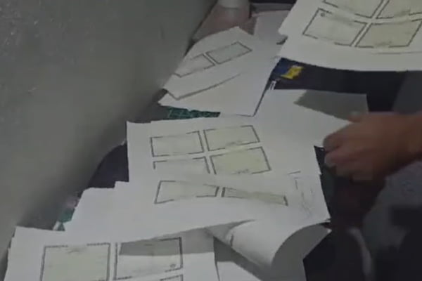 Imagem mostra folhas de papel impressas encontradas por policiais em local que falsificava documentos - Metrópoles