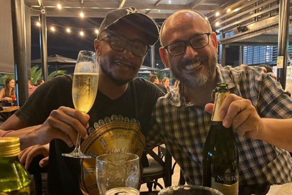 Imagem colorida mostra homens brindando com champanhe - Metrópoles