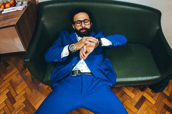 Murilo Couto deitado num sofá com terno azul