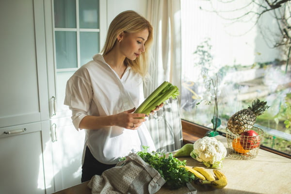 mulher segurando verduras na cozinha