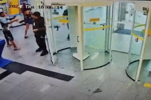 Imagem colorida de câmera de segurança mostra adolescente roubando arma de segurança de agência bancária no interior de São Paulo - Metrópoles