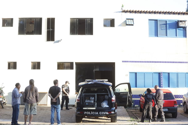 Prédio branco com viaturas na frente