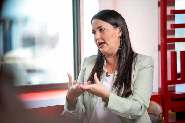 Foto colorida de secretária em entrevista. Mulher branca de cabelos longos e lisos