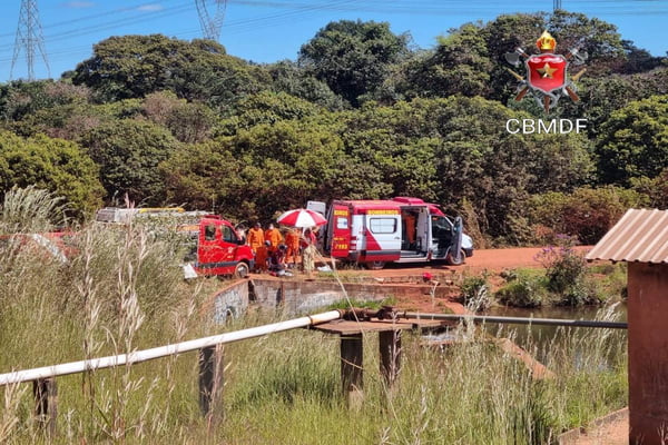 Foto colorida de viatura do bombeiro em local de barragem com céu azul