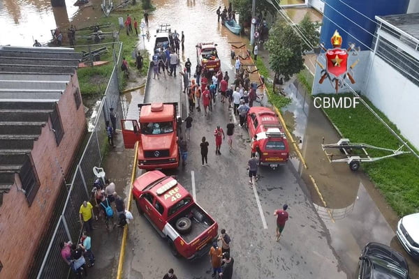 Foto colorida de bombeiros resgatando pessoas em enchete