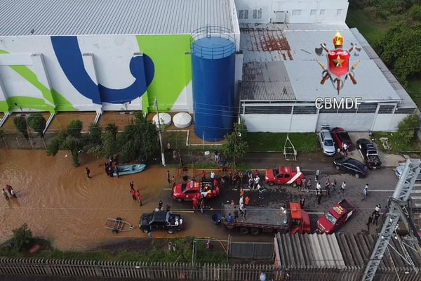 Foto colorida de bombeiros resgatando pessoas em enchete