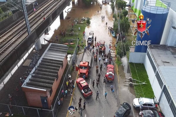 Foto colorida de bombeiros resgatando pessoas em enchete