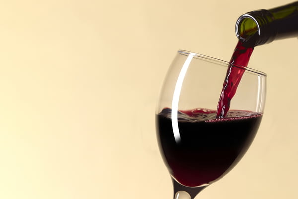 Foto colorida de vinho de garrafa sendo derramado dentro de taça - Metrópoles