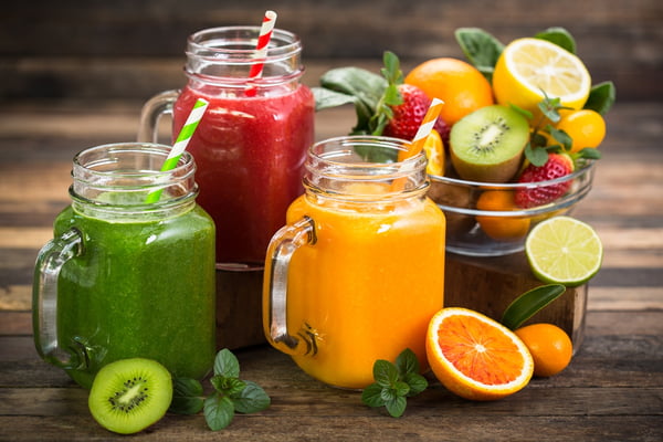 Imagem mostra três jarros com sucos coloridos e fatias de frutas - Metrópoles