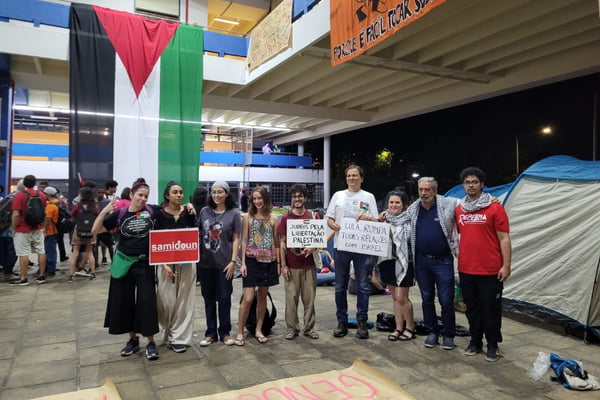 Estudante posam para foto com bandeira da palestina ao fundo