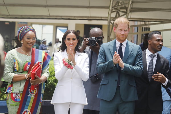 Foto colorida de mulher com roupa colorida ao lado de mulher com terno branco. Um homem ruivo com blazer e gravata azul também aparece na imagem - Metrópoles