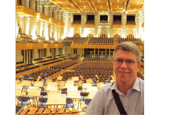 Homem branco, sem barba, de camisa social em palco de teatro usado em concertos musicais - Metrópoles