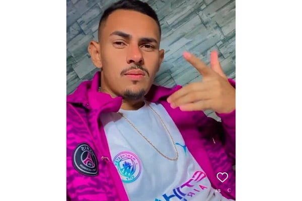 Rapaz pardo, de camiseta branca, sobre a qual jaqueta rosa, cavanhaque, fazendo sinal com a mão esquerda - Metrópoles