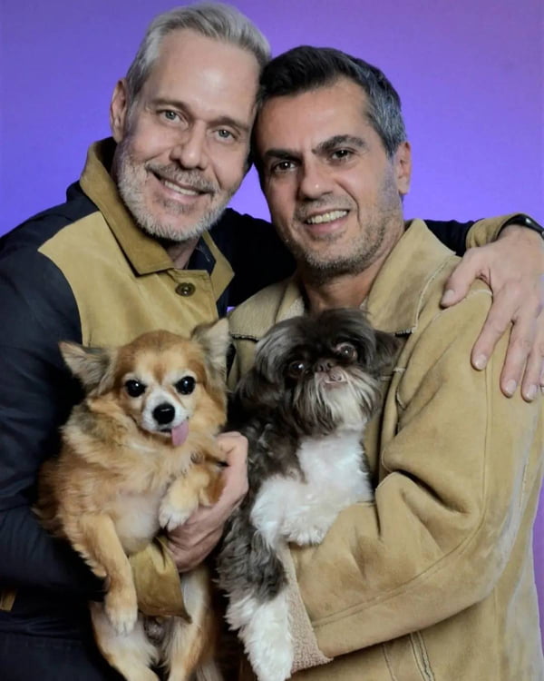 foto colorida de dois homens de meia idade com um cachorro no colo cada um - metrópoles