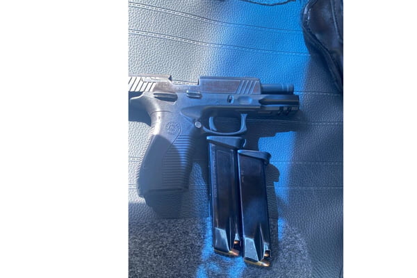 Foto colorida de pistola e dois carregadores, sob sol filtrado por vidraça azul - Metrópoles