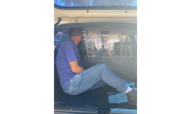 Foto colorida de homem de calça jeans clara, camiseta azul dentro de viatura da Polícia Civil - Metrópoles