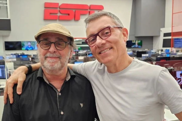 Imagem colorida mostra Antero Greco ao lado de Paulo Calçade na redação da ESPN - Metrópoles