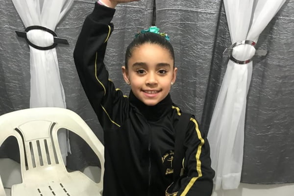Imagem colorida de menina com traje de balé. Metrópoles