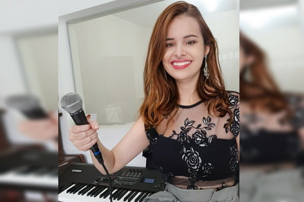 Foto de uma mulher segurando um microfone em frente a um teclado