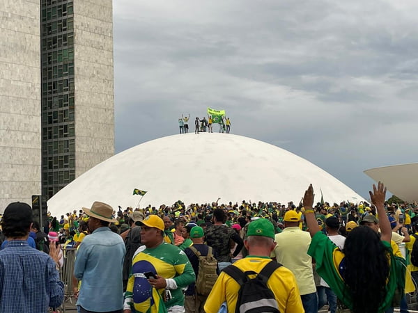 Imagem colorida de bolsonaristas em cima do Congresso Nacional