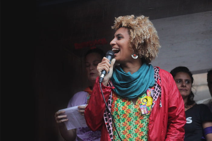 Foto colorida de Marielle Franco segurando microfone e sorrindo - Metrópoles