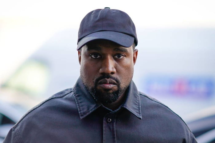 Foto colorida do rapper Kanye West, que está sério, de casaco e boné e olhando de frente para a câmera - Metrópoles