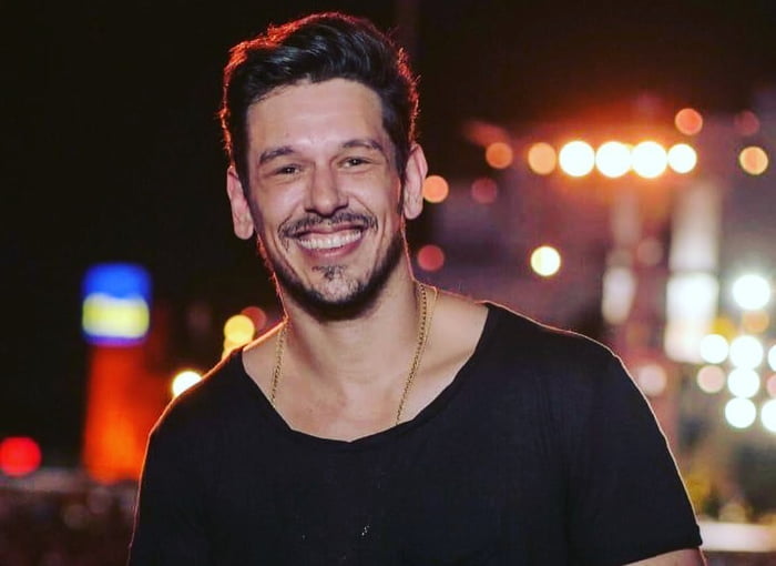 Foto colorida de João Vicente de Castro sorrindo e usando camiseta preta - Metrópoles