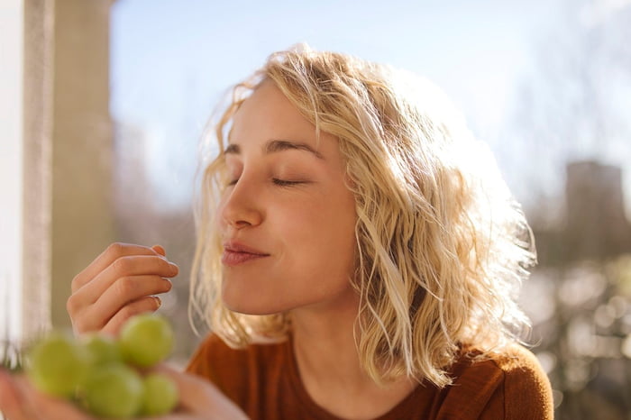 Imagem colorida de mulher comendo uvas - Metrópoles