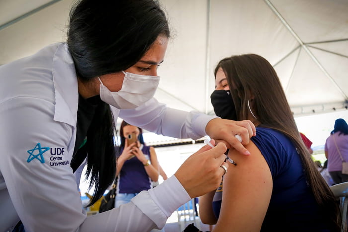 Enfermeira vacinando jovem