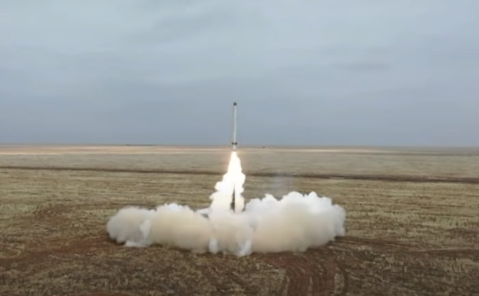 Mísseis lançados por Rússia em exercício militar. Num campo deserto, sob céu nublado, vê-se muita fumaça ao redor de um míssel em lançamento - Metrópoles