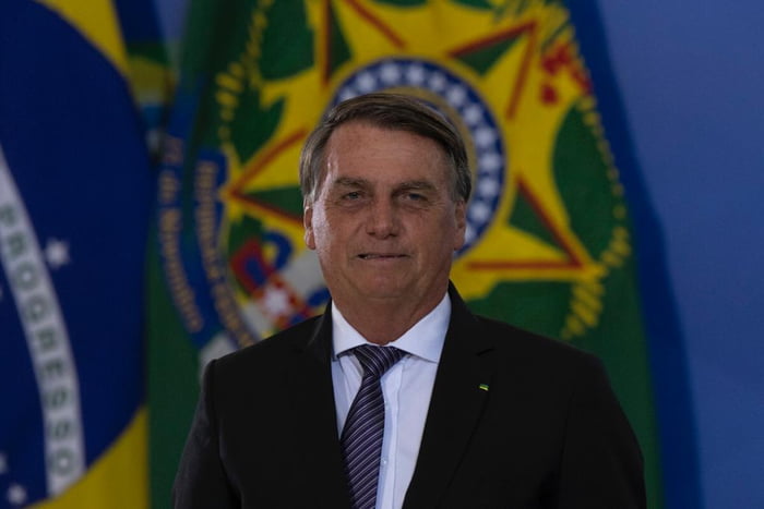 O presidente Bolsonaro cumprimenta os Oficiais-Generais promovidos na cerimônia realizada no palácio do Planalto. Ele está diante de bandeira do Brasil - Metrópoles