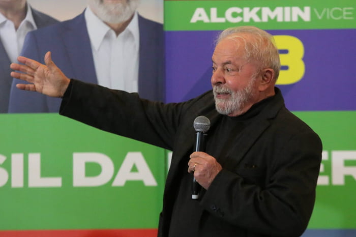 O ex-pO ex-presidente Luiz Inácio Lula da Silva (PT) aponta para lado com cartaz de campanha ao fundo