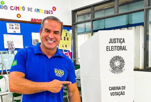 O apresentador e deputado federal eleito, Fred Linhares, vota com camiseta azul apontando para urna eletrônica - Metrópoles