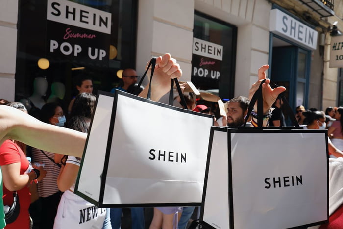 Pessoas carregam sacolas brancas com logotipo da Shein fast fashion - Metrópoles